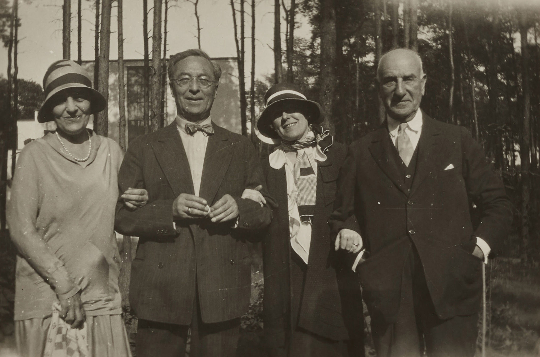 A black-and-white photograph of Irene Guggenheim, Kandinsky, Hilla Rebay, and Solomon R. Guggenheim standing arm in arm at the Bauhaus in Dessau.